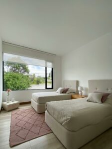 A bedroom with two beds and a side table between them.