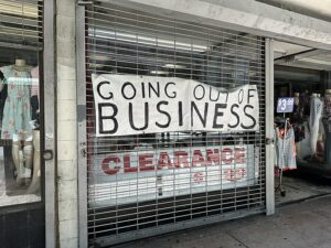 A sign hung on the gates of a closed shop that reads “going out of business.” 