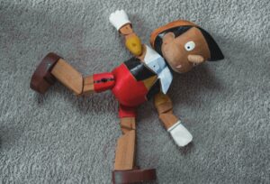 A Pinocchio doll laying on the ground. 