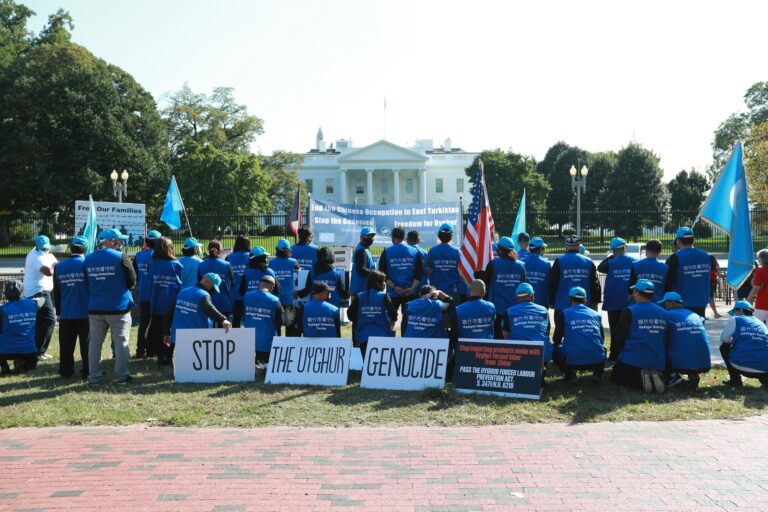 A group of people with a sign that says "Stop the Uyghur genocide."