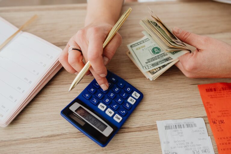 A person using a calculator with money in their hand.