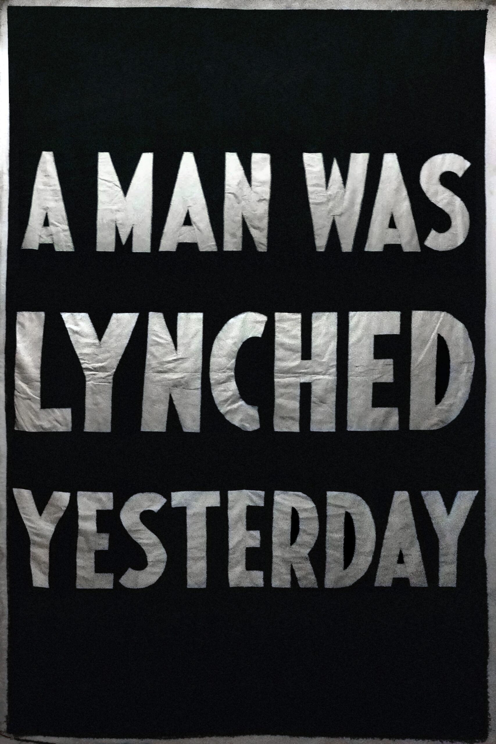 A black poster reading “A man was lynched yesterday” in thick white capital letters.