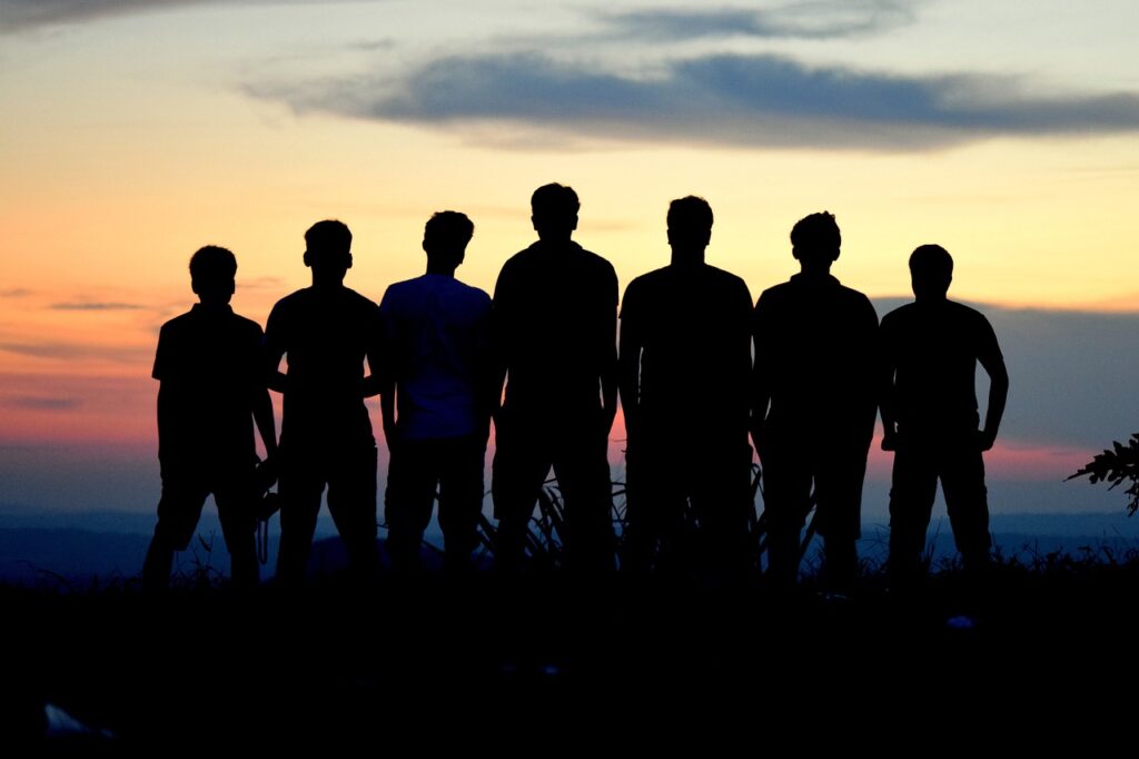 A group of people standing in front of a sunset.