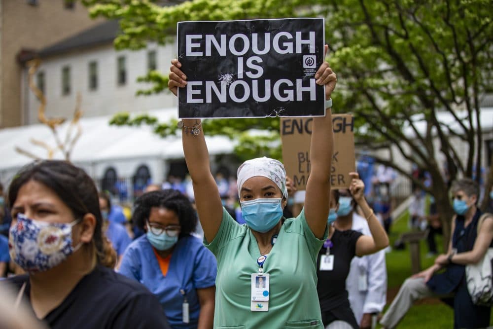 A medical worker at a protest holding a sign that says "enough is enough."